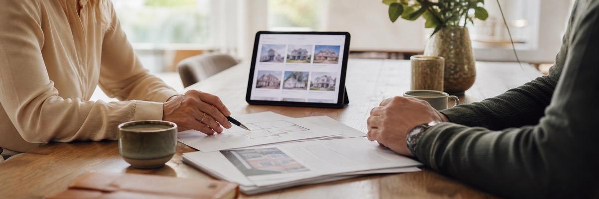Aankoopgesprek aan tafel met woninginformatie en tablet